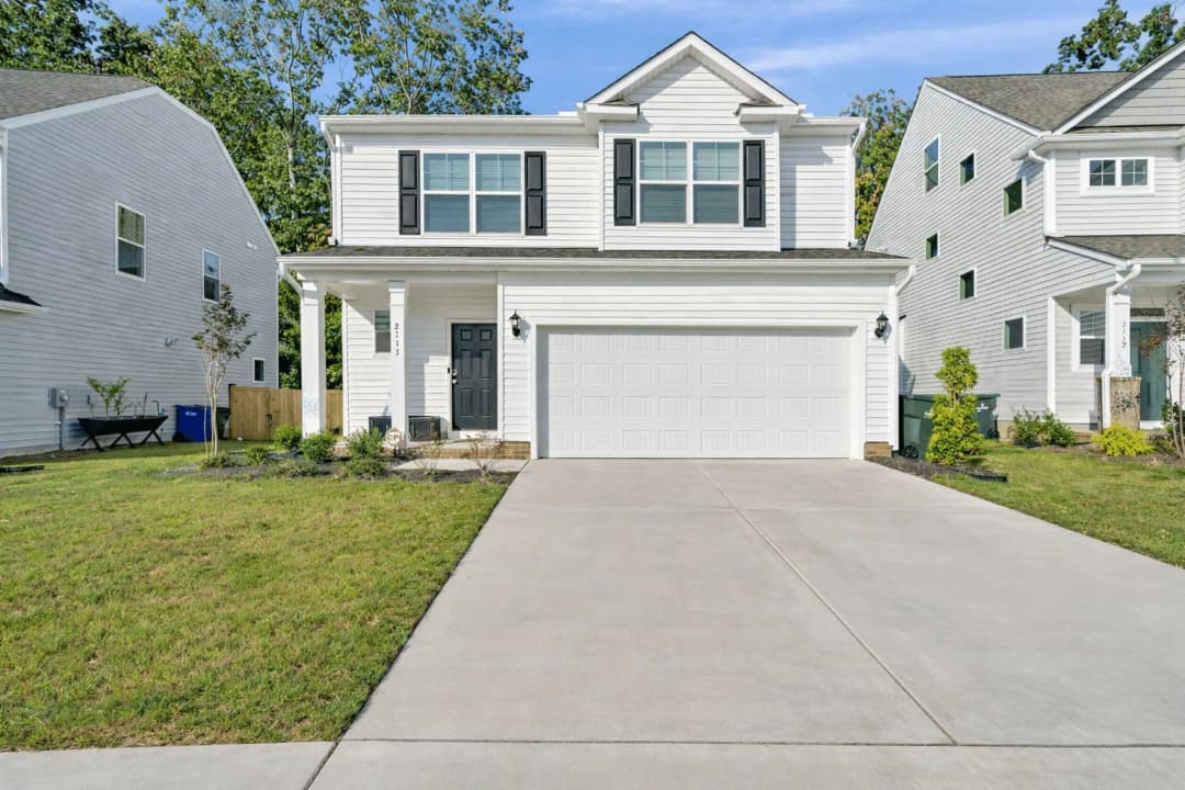 Two-story white home with a two-car garage and private driveway in a residential Raleigh neighborhood